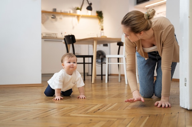 Foto gratuita madre de tiro completo enseñando al bebé a gatear