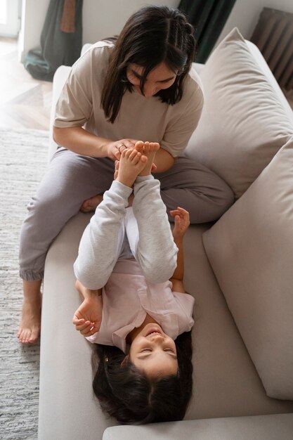 Madre de tiro completo haciendo cosquillas al niño en el sofá