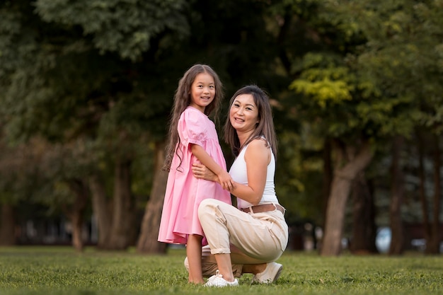 Foto gratuita madre de tiro largo sosteniendo a su hija al aire libre