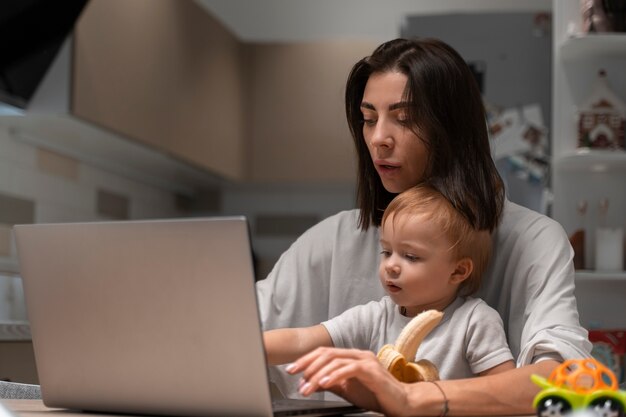 Madre de tiro medio trabajando y sosteniendo al bebé