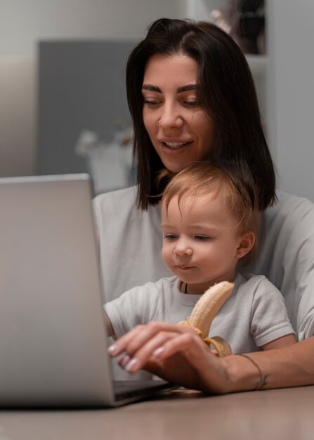 Madre de tiro medio trabajando y sosteniendo al bebé