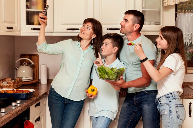 Madre tomando selfie con familia en la cocina antes de la cena