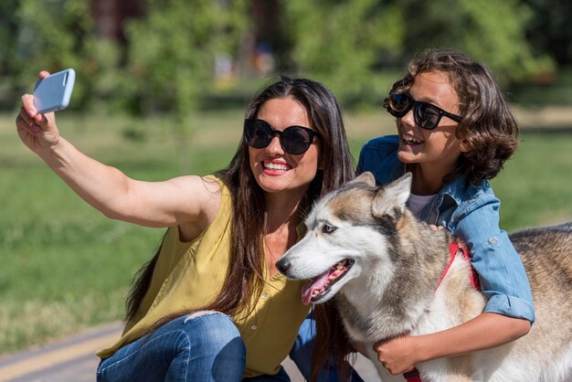 Madre tomando selfie de hijo y perro en el parque