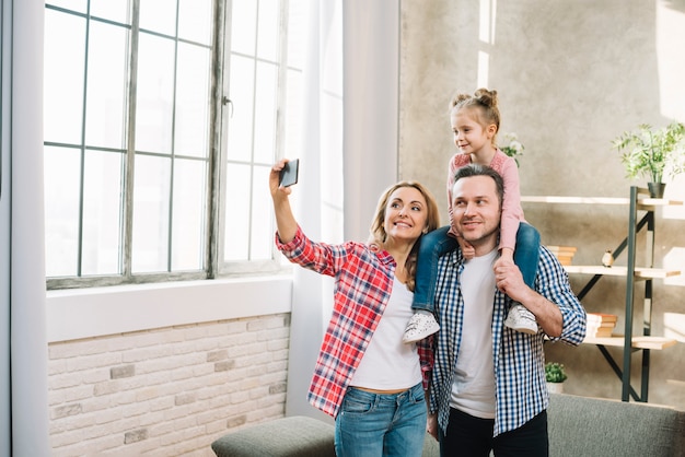 Madre tomando selfie en el teléfono móvil con su marido y su hija