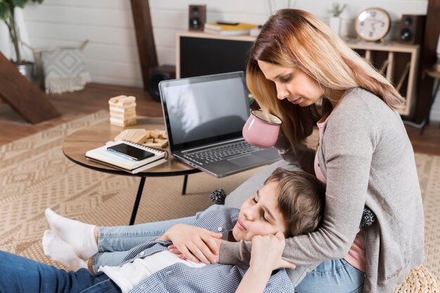 Madre trabajando desde casa y abrazando a su hijo