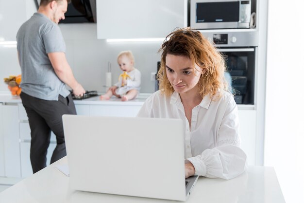 Madre trabajando en la computadora portátil en la cocina