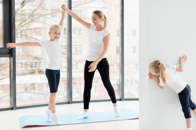 Madre trabajando con hijas en casa en estera de yoga