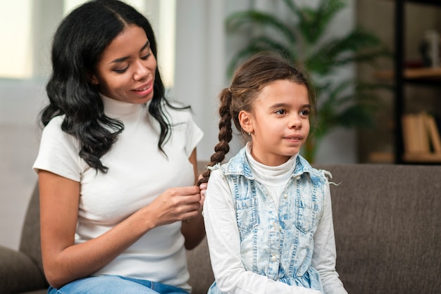 Foto gratuita madre trenzando el cabello de su hija