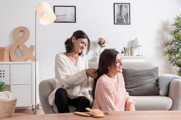 Madre trenzando el cabello de su hija