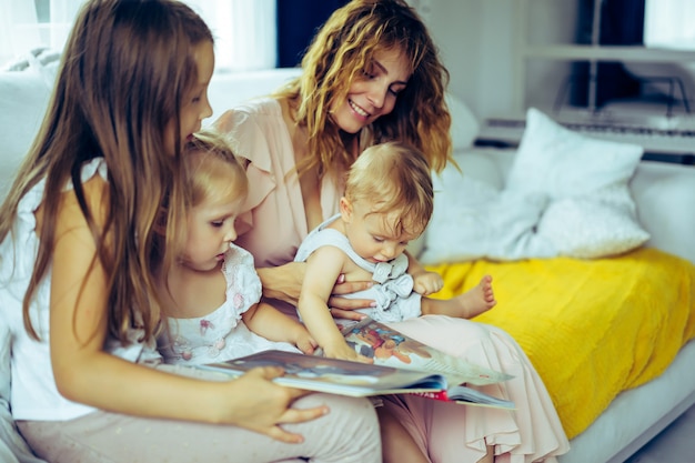 Madre con tres hijos leyendo un libro en un ambiente hogareño.