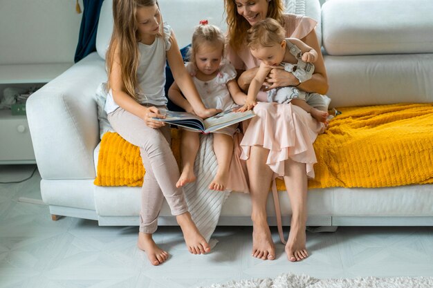 Madre con tres hijos leyendo un libro en un ambiente hogareño.