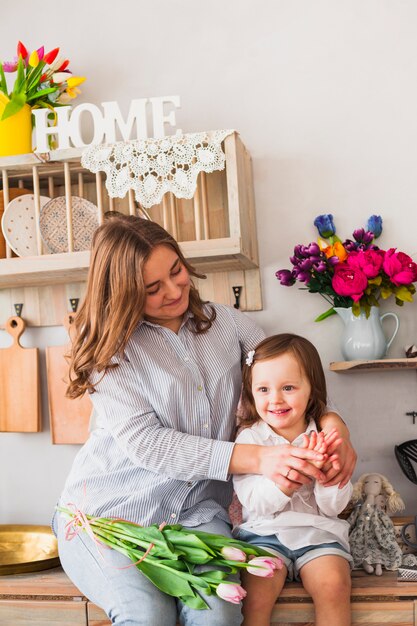 Madre con tulipanes abrazando a hija