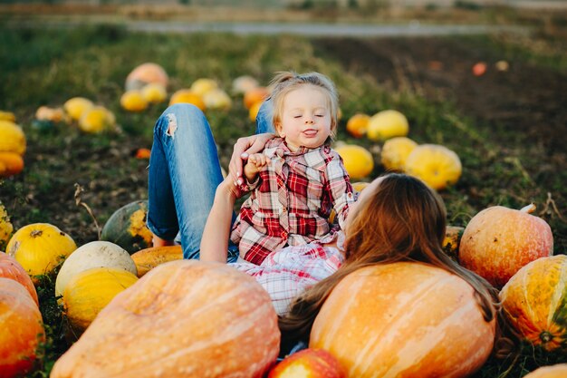 Madre tumbada sobre calabazas con las piernas en alto y la hija en su estómago