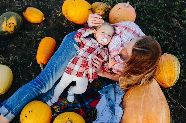 Madre tumbada sobre calabazas sujetando a su hija en su barriga