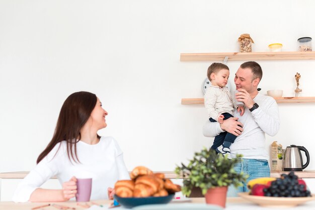 Madre viendo padre con niño en la cocina