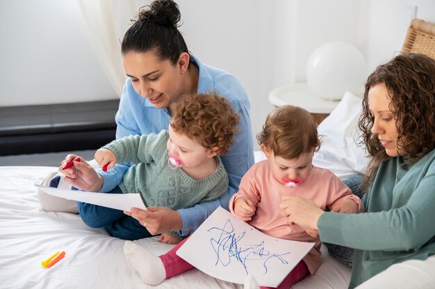 Madres LGBT en casa en el dormitorio con sus hijos