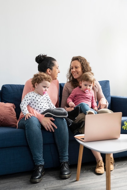 Foto gratuita madres lgbt en casa con niños en el sofá.