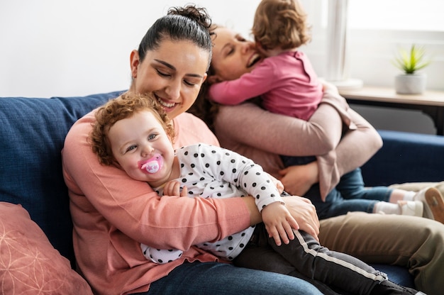 Madres LGBT en casa en el sofá con niños