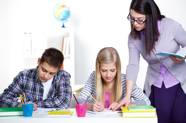 Maestra corrigiendo errores en el cuaderno de la alumna