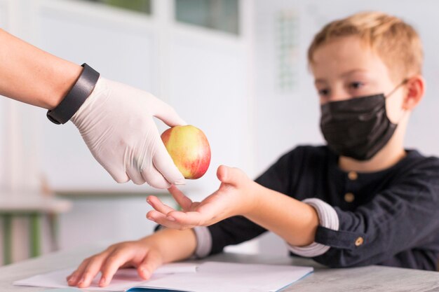 Maestra dando una manzana a su alumno