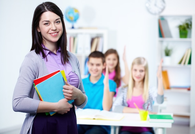 Maestra feliz con alumnos de fondo