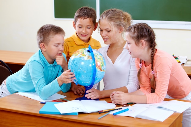 Maestra de geografía y estudiantes mirando el globo