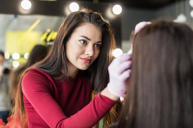 Foto gratuita maestra haciendo maquillaje profesional de mujer joven