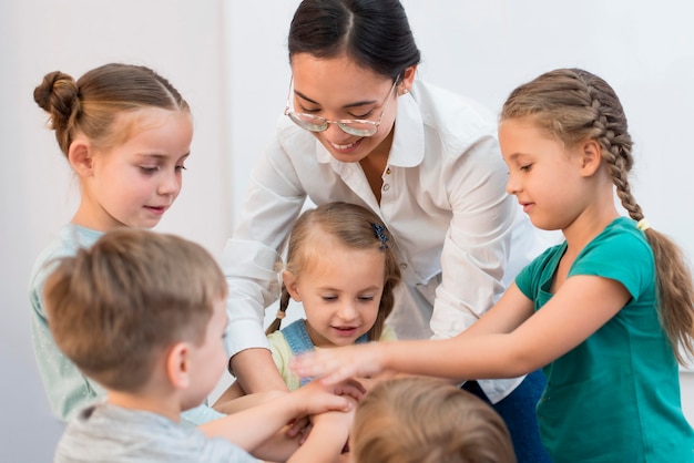 Maestra juntando sus manos con sus alumnos para un juego