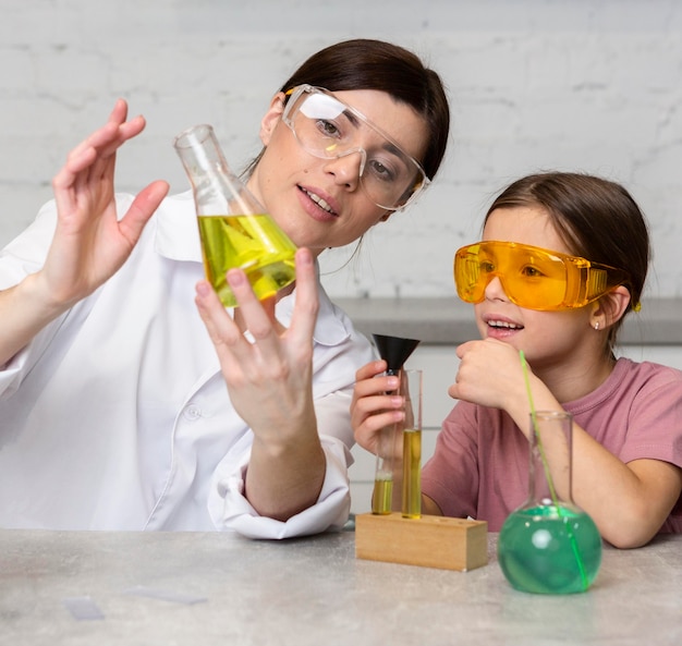Maestra y niña haciendo experimentos científicos con tubos de ensayo