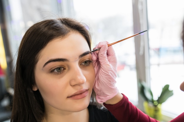 Maestra pone pintura de cejas en salón de belleza durante el maquillaje