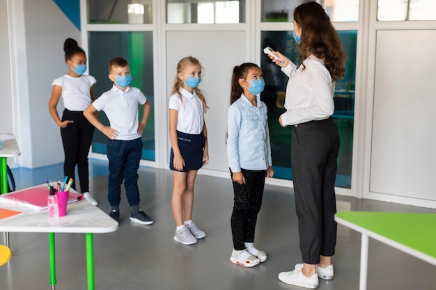 Foto gratuita maestra tomando la temperatura de sus alumnos