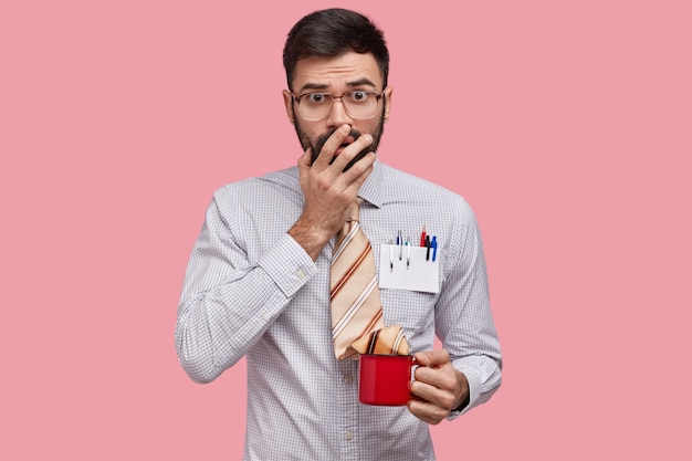 El maestro asustado cubre la boca, tiene expresión de sorpresa, vestido con ropa formal