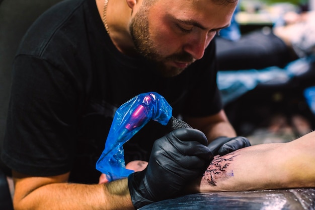 Maestro haciendo tatuajes con hierro en el salón