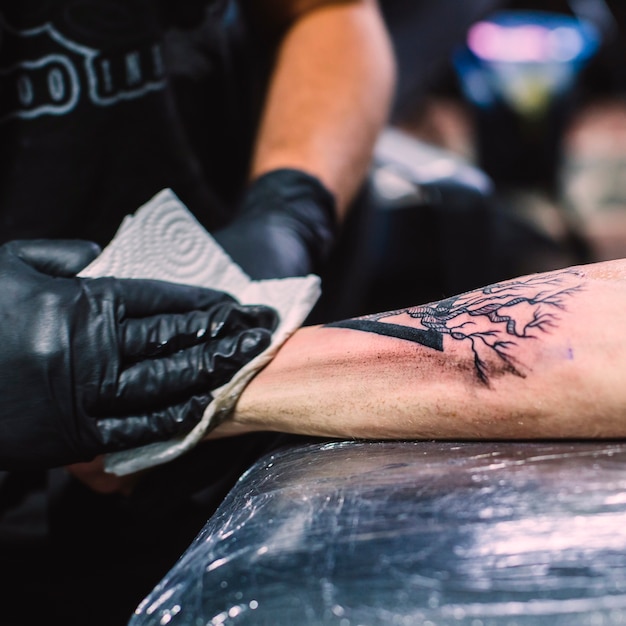 Foto gratuita maestro limpiando el tatuaje en el brazo