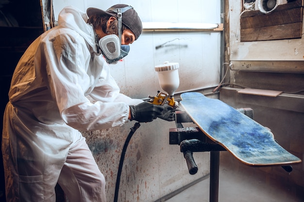 Maestro pintor en una fábrica - pintura industrial de madera con pistola