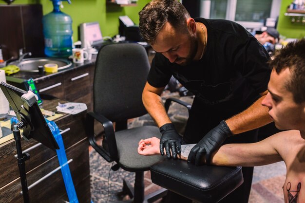 Maestro poniendo borrador de tatuaje en el brazo