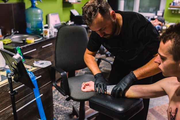 Maestro poniendo borrador de tatuaje en el brazo