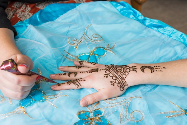 Maestro tatuando mehndi dibuja en mano de dama