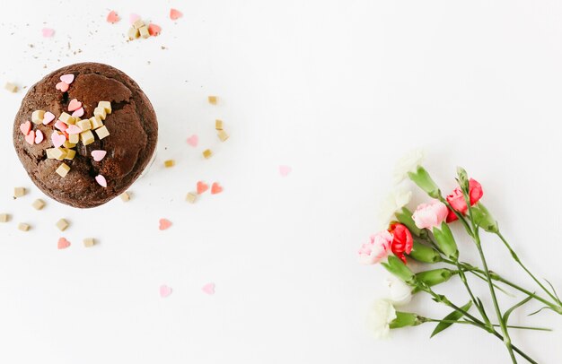 Magdalena del chocolate con las flores en el fondo blanco