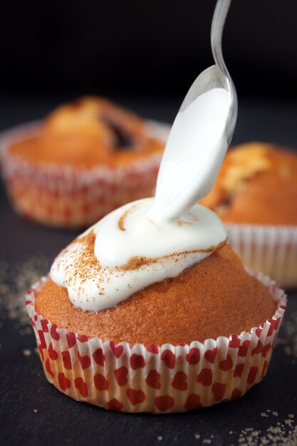 Magdalenas con crema por encima y una cuchara