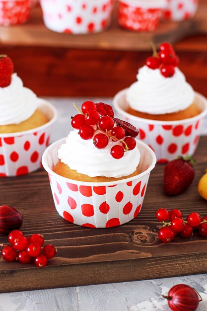 Magdalenas dulces de vainilla con relleno de mermelada de bayas y crema de queso, decoradas con bayas de verano