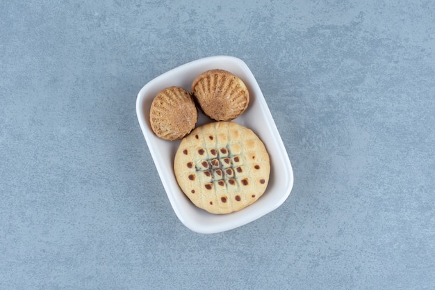 Magdalenas frescas con galleta en tazón de fuente blanco.