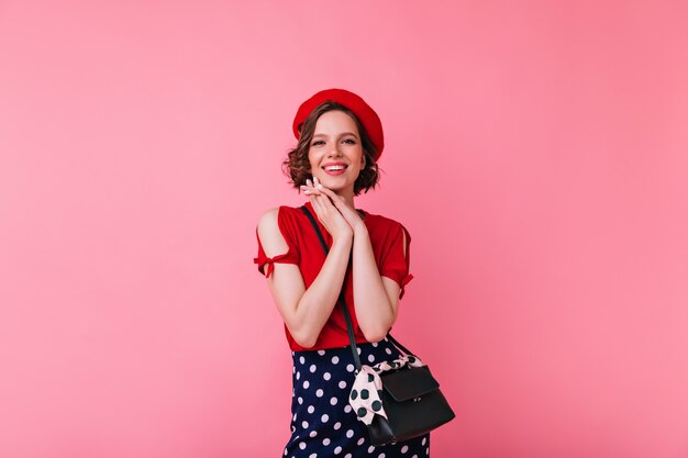 Magnífica chica blanca en traje glamoroso posando. Jocund mujer francesa en boina de pie con linda sonrisa.