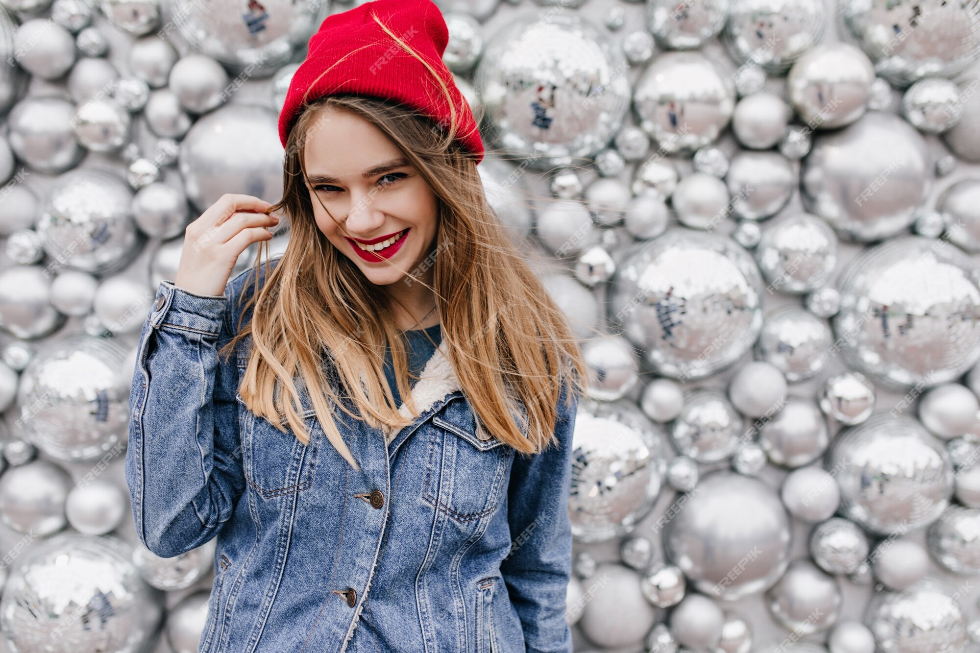 Magnífica mujer blanca con elegante chaqueta vaquera con el pelo largo. sonriente niña emocionada con rojo de pie de bolas de discoteca. | Foto Gratis