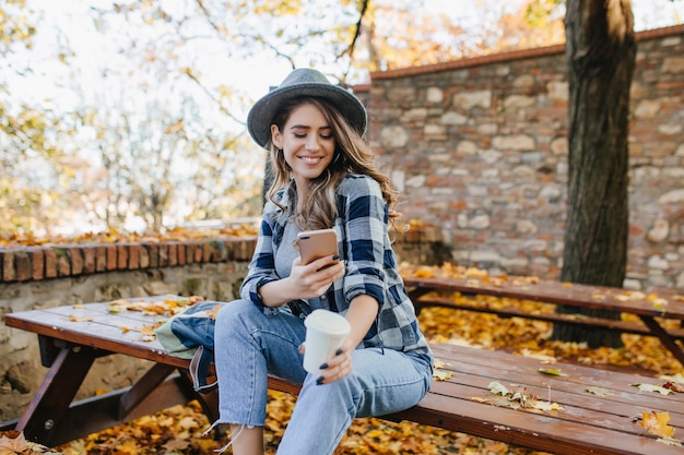 Magnífica mujer blanca usa ropa casual mensaje de texto en buen día de septiembre