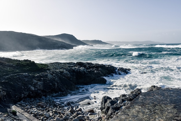 Magníficas olas del mar llegando a las hermosas rocas de la playa en un día nublado