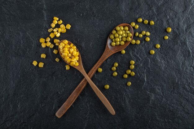 Maíz enlatado y guisantes con cucharas.