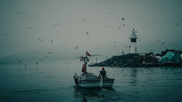 Majestuosa vista posterior de un pescador en un barco navegando con una increíble escena de la naturaleza