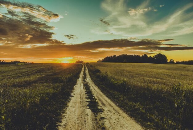 Majestuosa vista de la puesta de sol sobre un paisaje con un camino sin asfaltar que desaparece en el horizonte