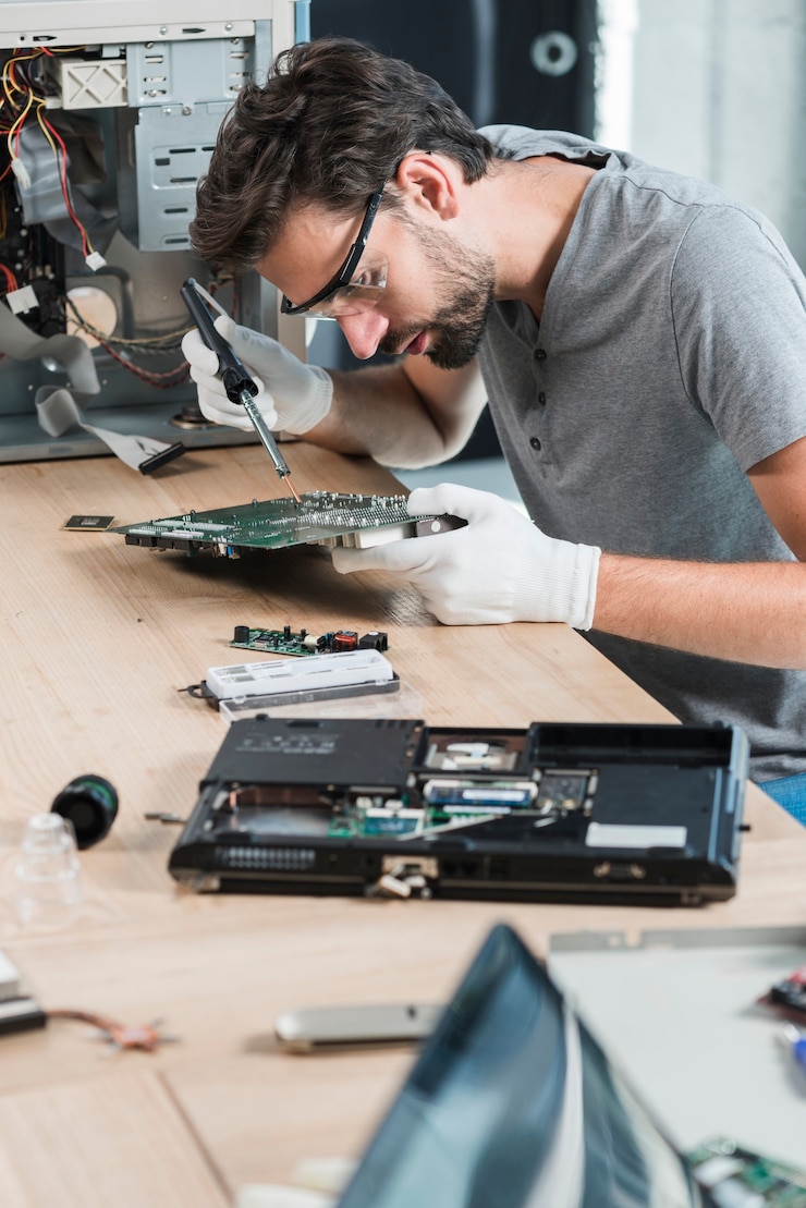 Photo Gratis male technician repairing computer motherboard on wooden desk